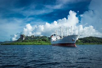 An elegant ship anchored near a pristine island with white sandy beaches.