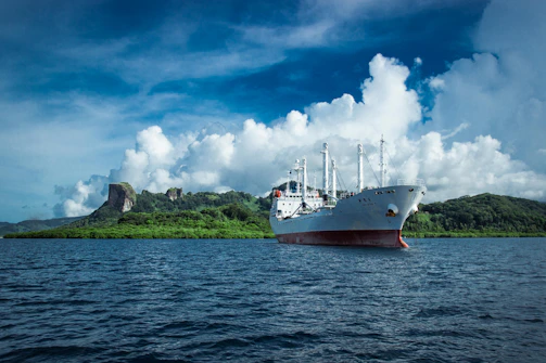 An elegant ship anchored near a pristine island with white sandy beaches.