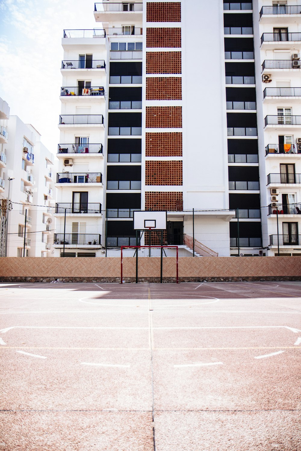 Aro de baloncesto blanco cerca de un edificio de hormigón blanco y marrón