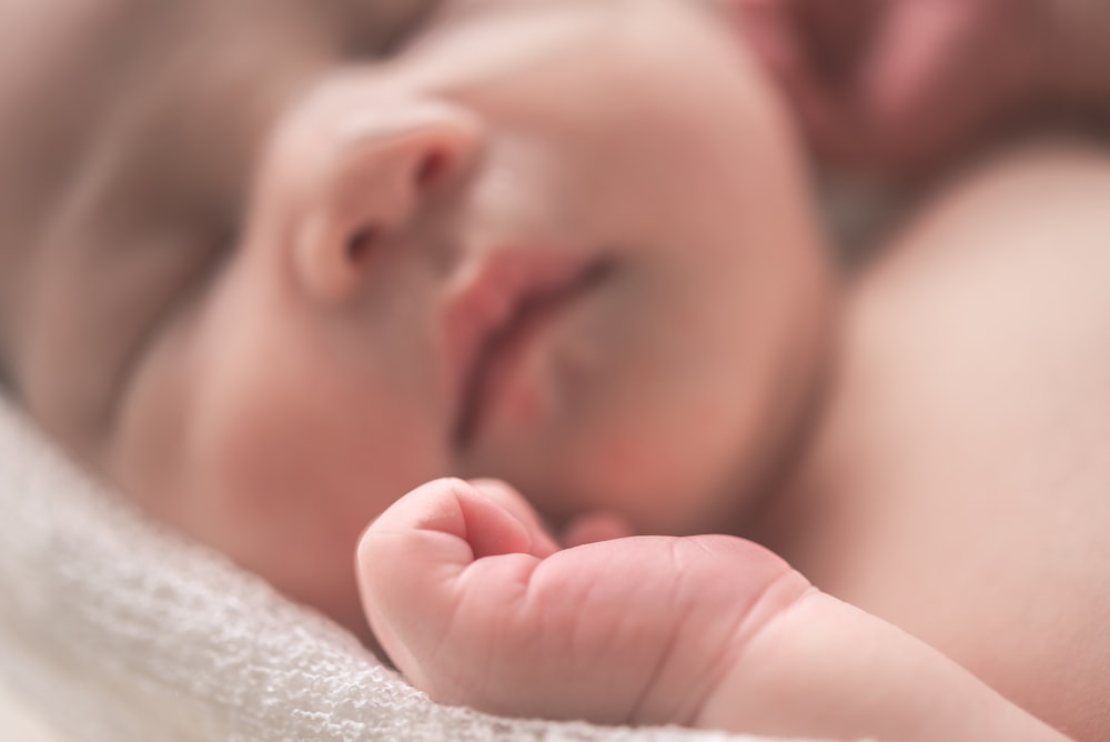 sleeping baby on white textile