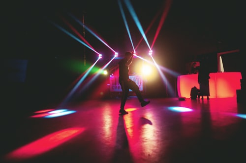Neon-lit nightclub dance floor with a dancer silhouette