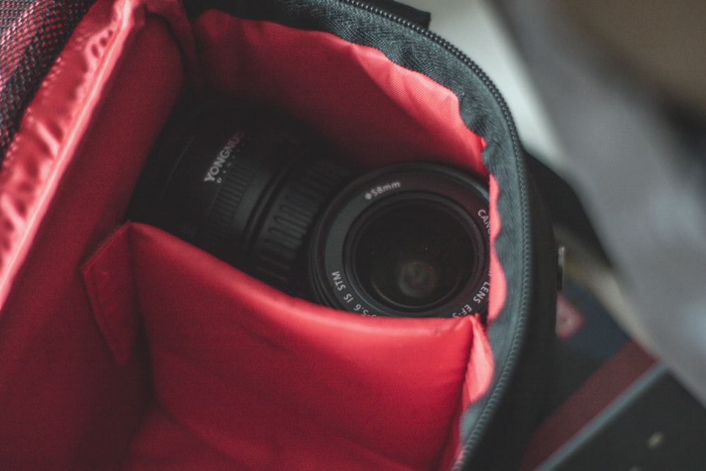 shallow focus photo of black camera lens on black and red bag