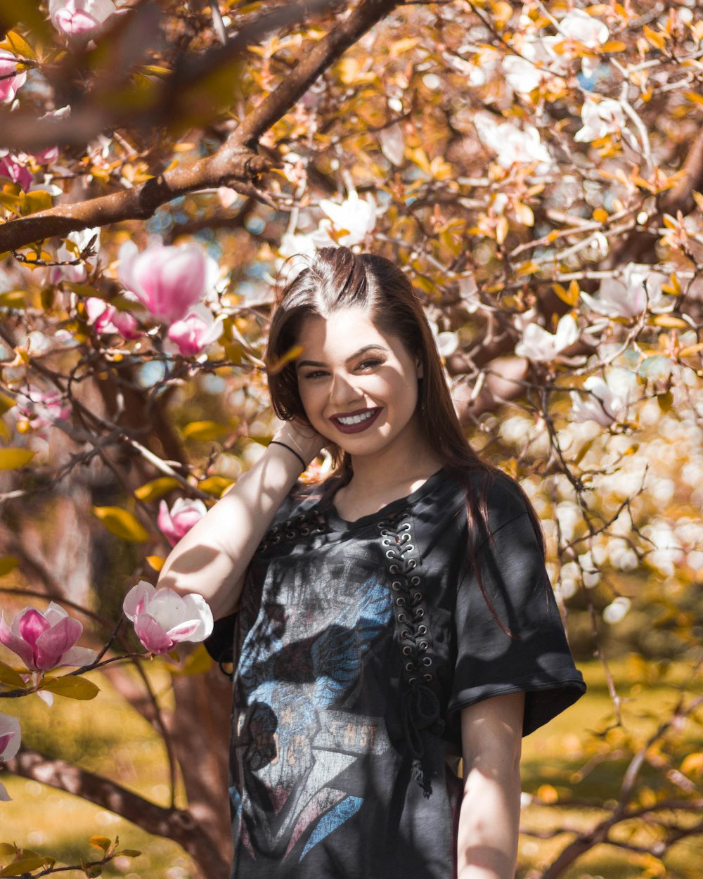 femme souriant sous l’arbre de fleurs roses