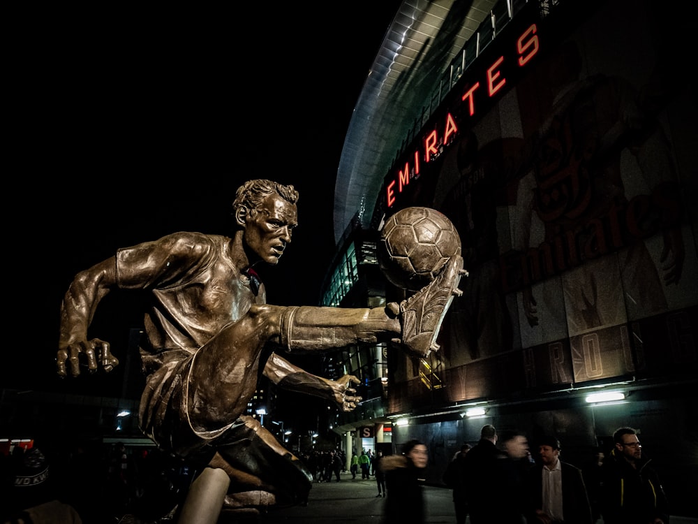 homme jouant à la statue de ballon de football