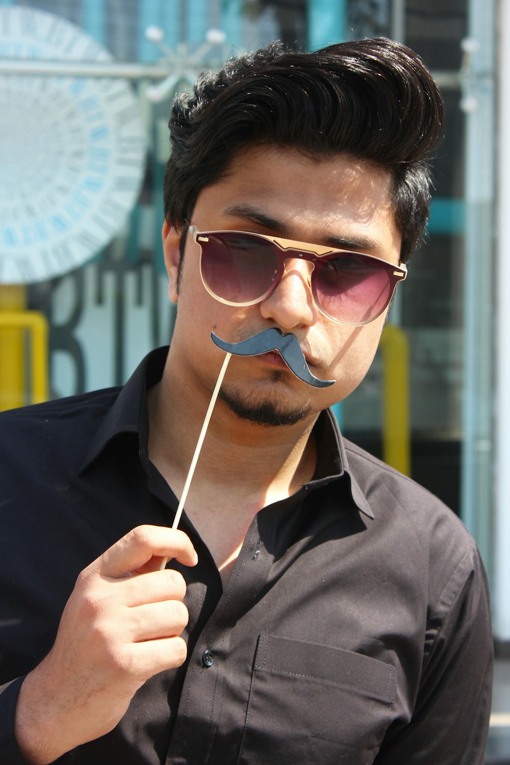 Homem segurando adereços de festa de bigode preto