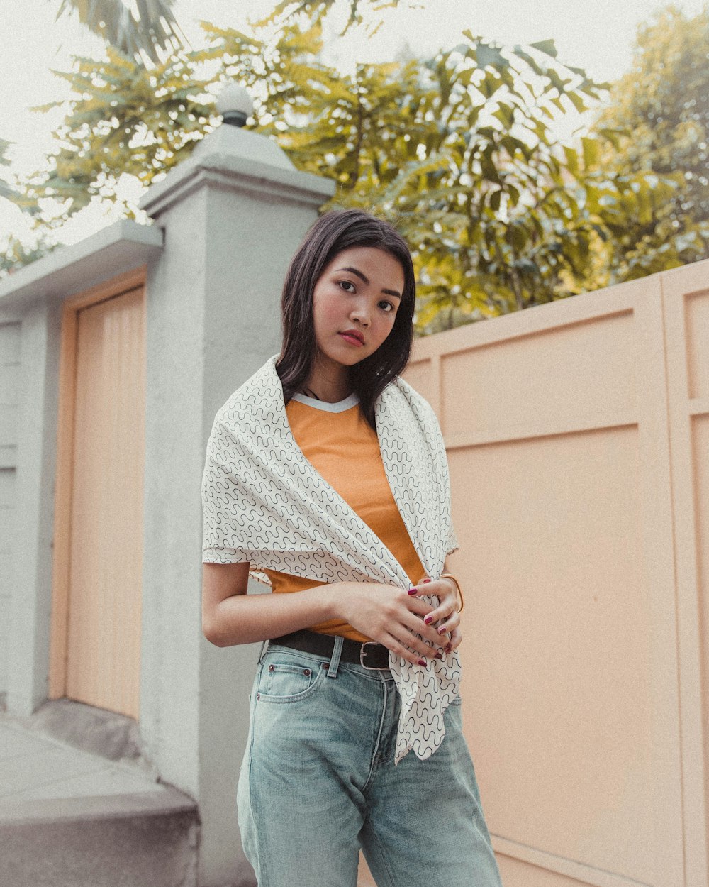 woman covering her body with scarf standing near beige gate