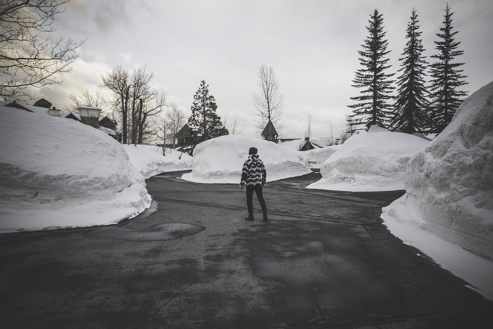 fotografia in scala di grigi dell'uomo circondato dalla neve