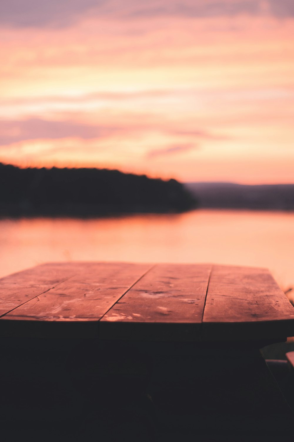 a wooden table sitting in front of a body of water