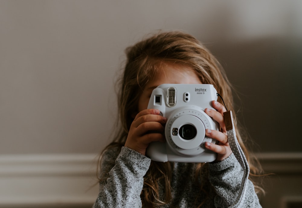 Ragazza che scatta una foto usando la macchina fotografica istantanea