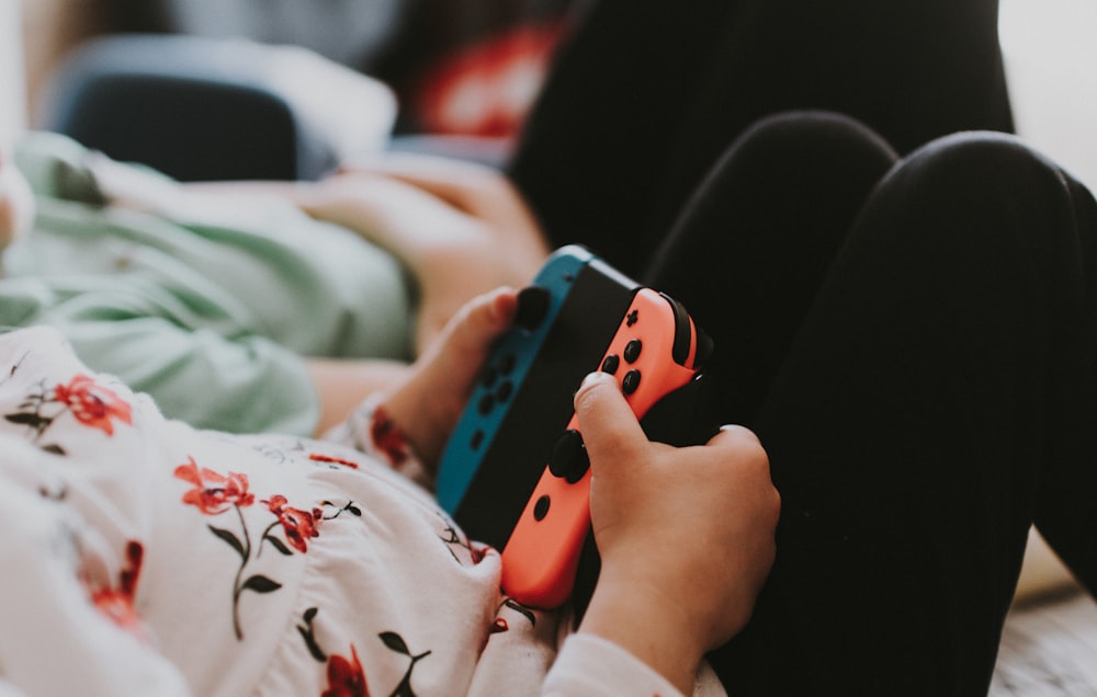 person holding blue and orange Joy Con controller