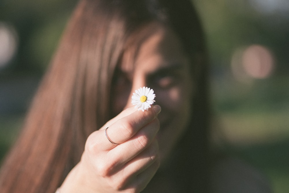 selective focus photo of woman holding white aster flower