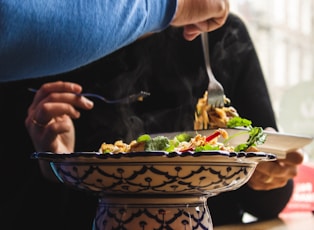 selective focus photography of person holding fork picking on cooked food