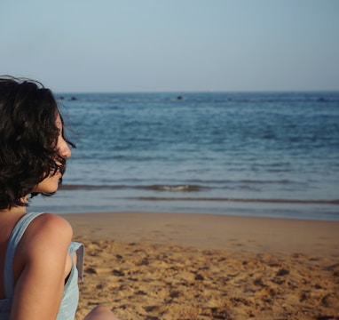 woman standing beach sand facing waves