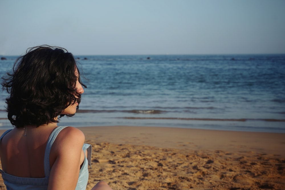 woman standing beach sand facing waves