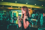 woman lifting black and gray barbell