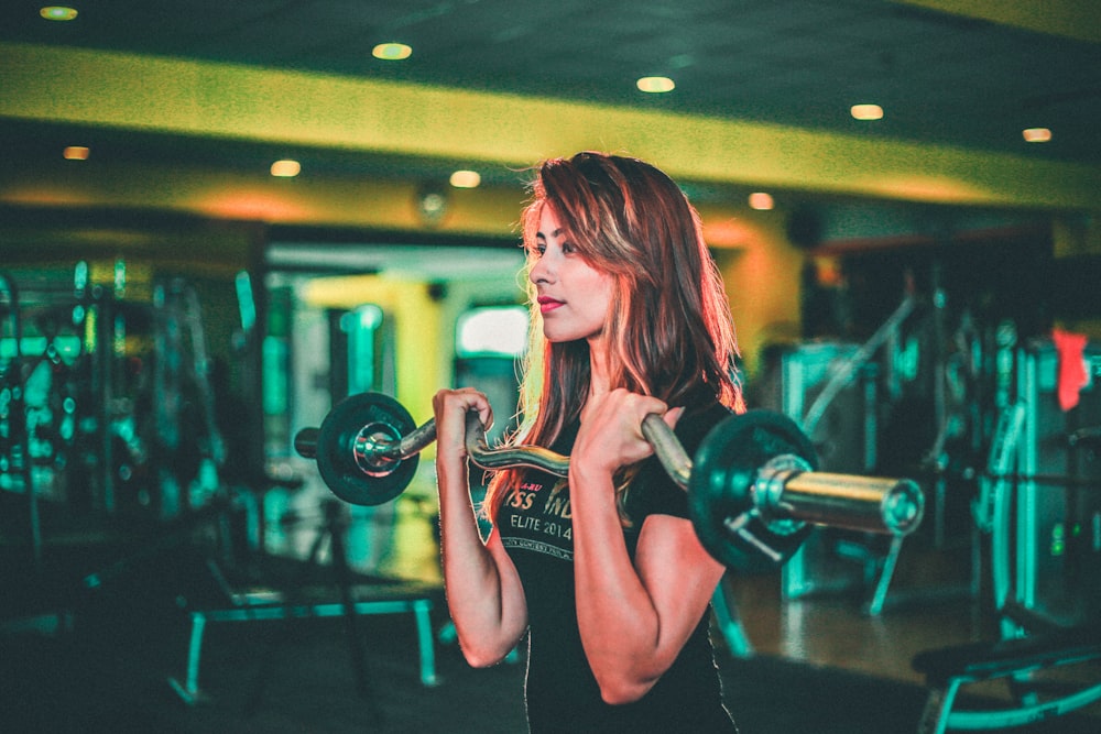 woman lifting black and gray barbell