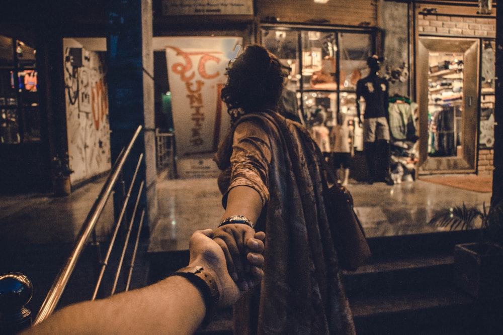 person holding another hand of person standing near stairs