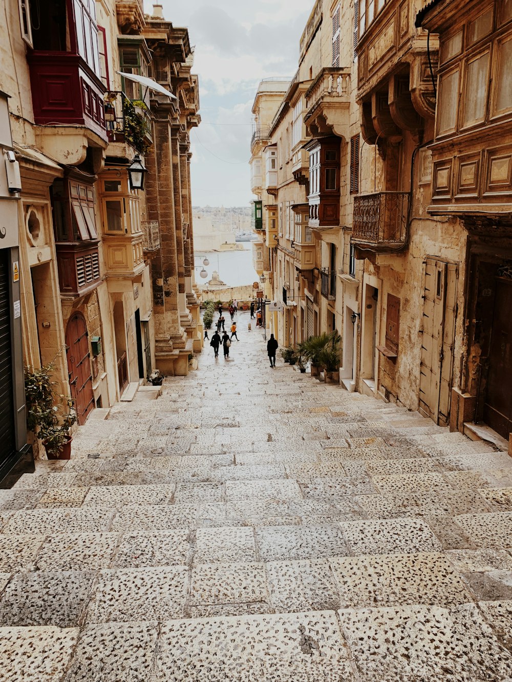 people walking on stairs between brown buildings during daytime