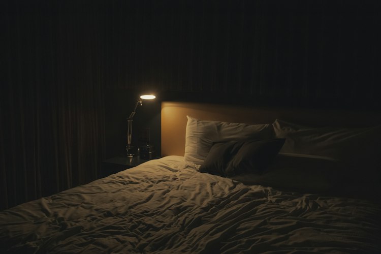 A person reviewing sleep data on a phone screen while sitting up in bed in the morning