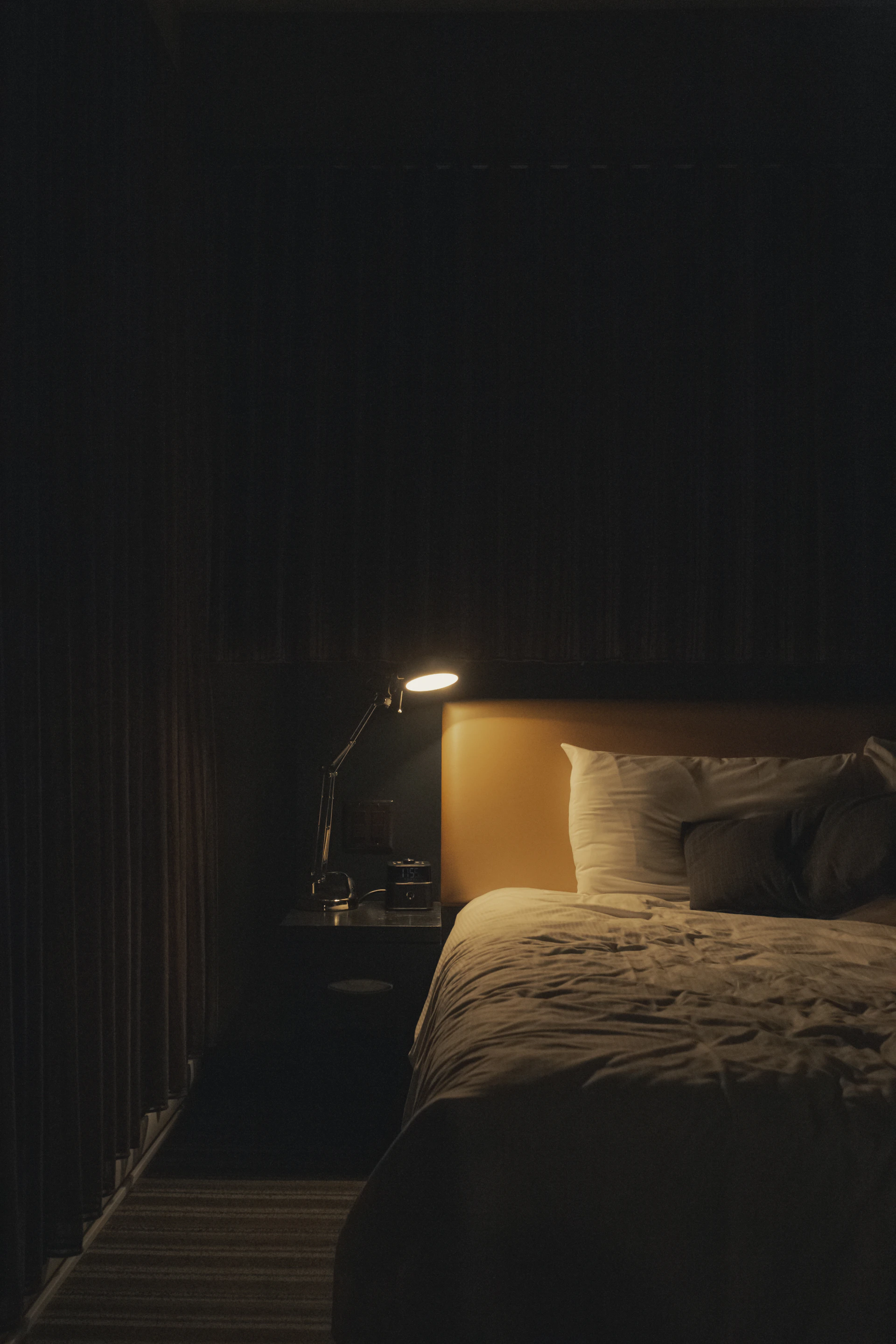 Lit aux oreillers blancs dans une chambre éclairée par une lampe chaude