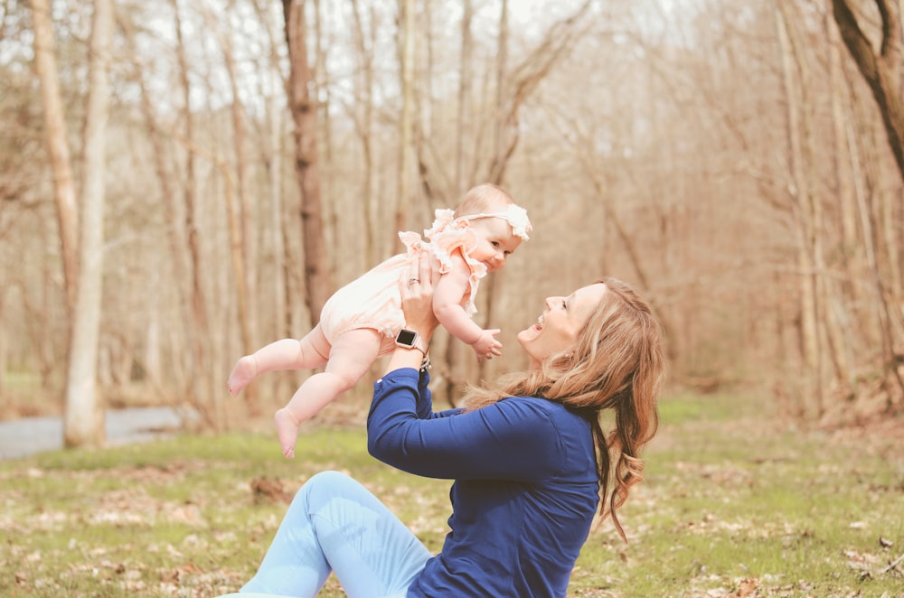 woman carrying child while sitting on ground