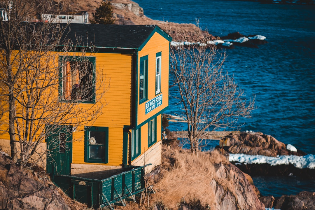 yellow and green wooden 2-storey house near cliff during daytime