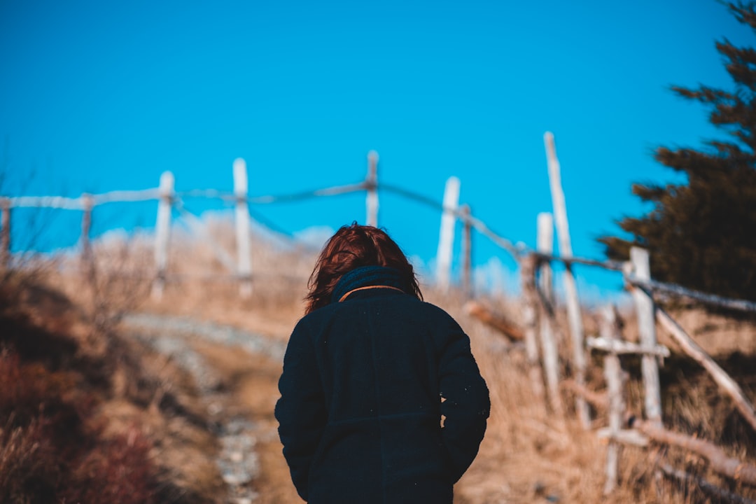 selective focus photography of person wearing blue coat walking on steep hill during daytime