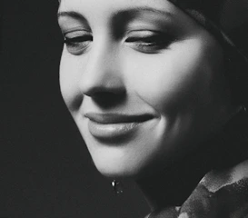 A serene black and white portrait of an elderly woman smiling softly.