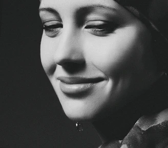 A serene portrait of a woman in her forties smiling gently in natural light.