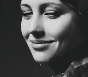 A serene black and white portrait of an elderly woman smiling softly.