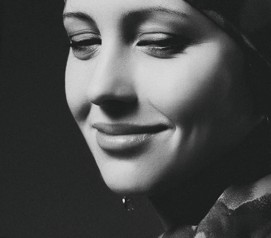 A serene portrait of a woman in her forties smiling gently in natural light.