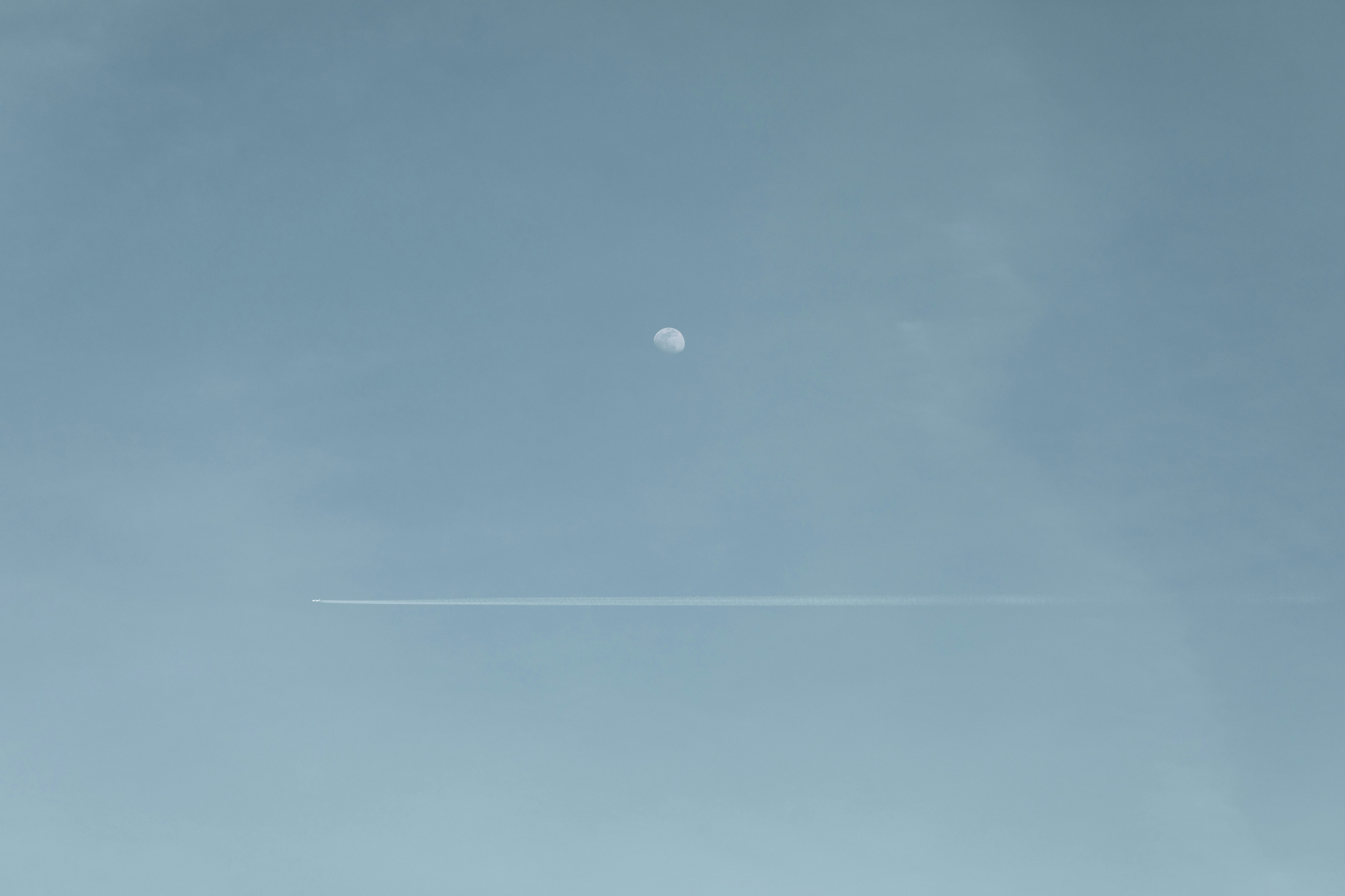 a plane flying in the sky with a moon in the background