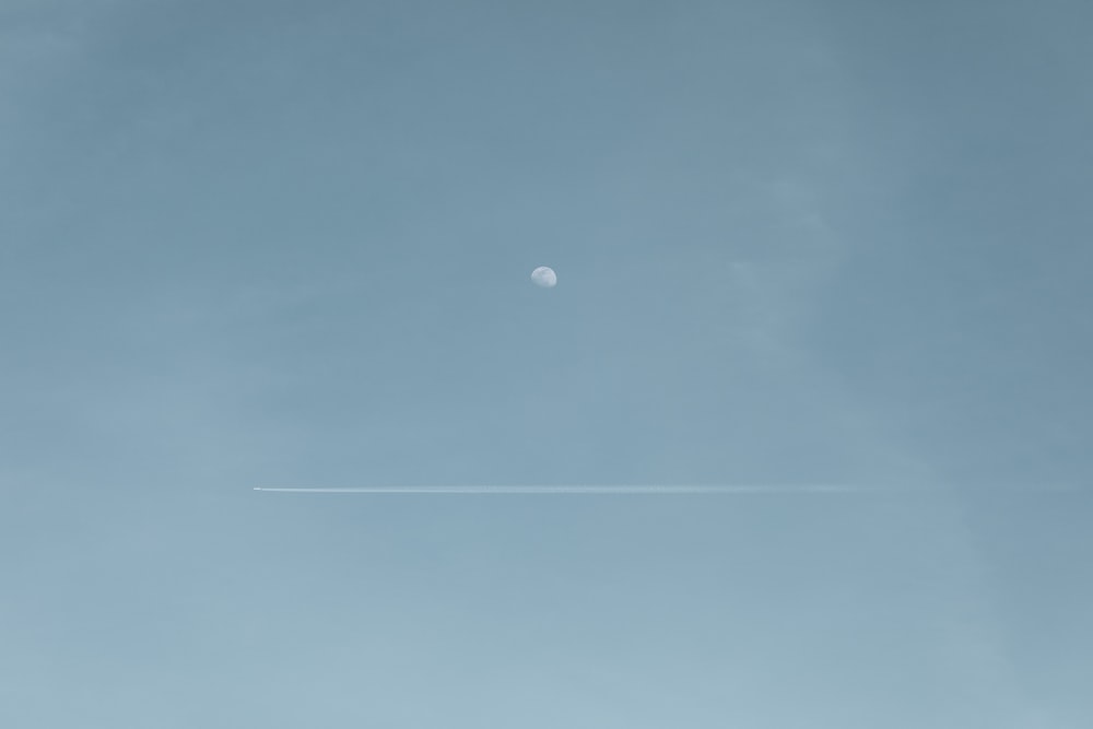 Ein Flugzeug, das mit einem Mond im Hintergrund am Himmel fliegt