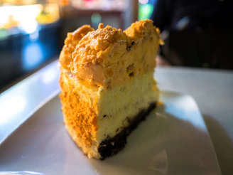 An overhead shot of a cheesecake being sliced with a golden knife, showing its creamy texture and crumbly base