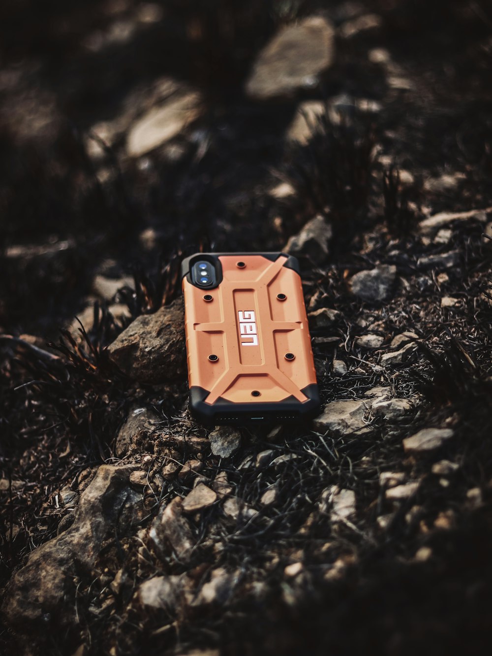 rectangular orange and black UAG smartphone on ground