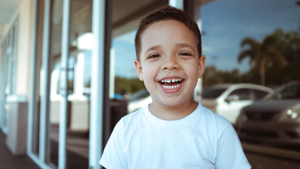 smiling boy wearing white crew-neck t-shirt during daytime