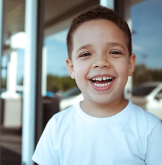 smiling boy wearing white crew-neck t-shirt during daytime