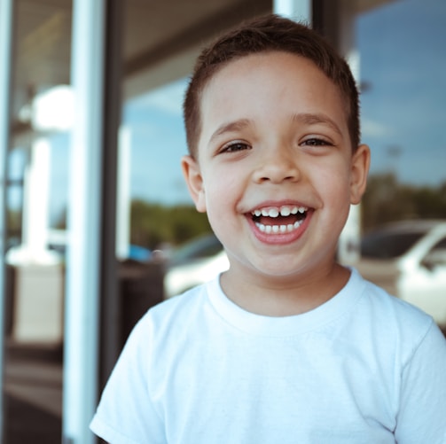 smiling boy wearing white crew-neck t-shirt during daytime