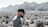man standing beside grass near mountain