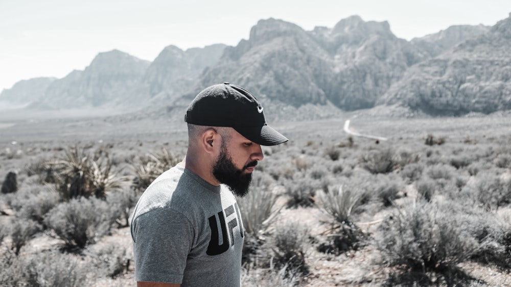 man standing beside grass near mountain