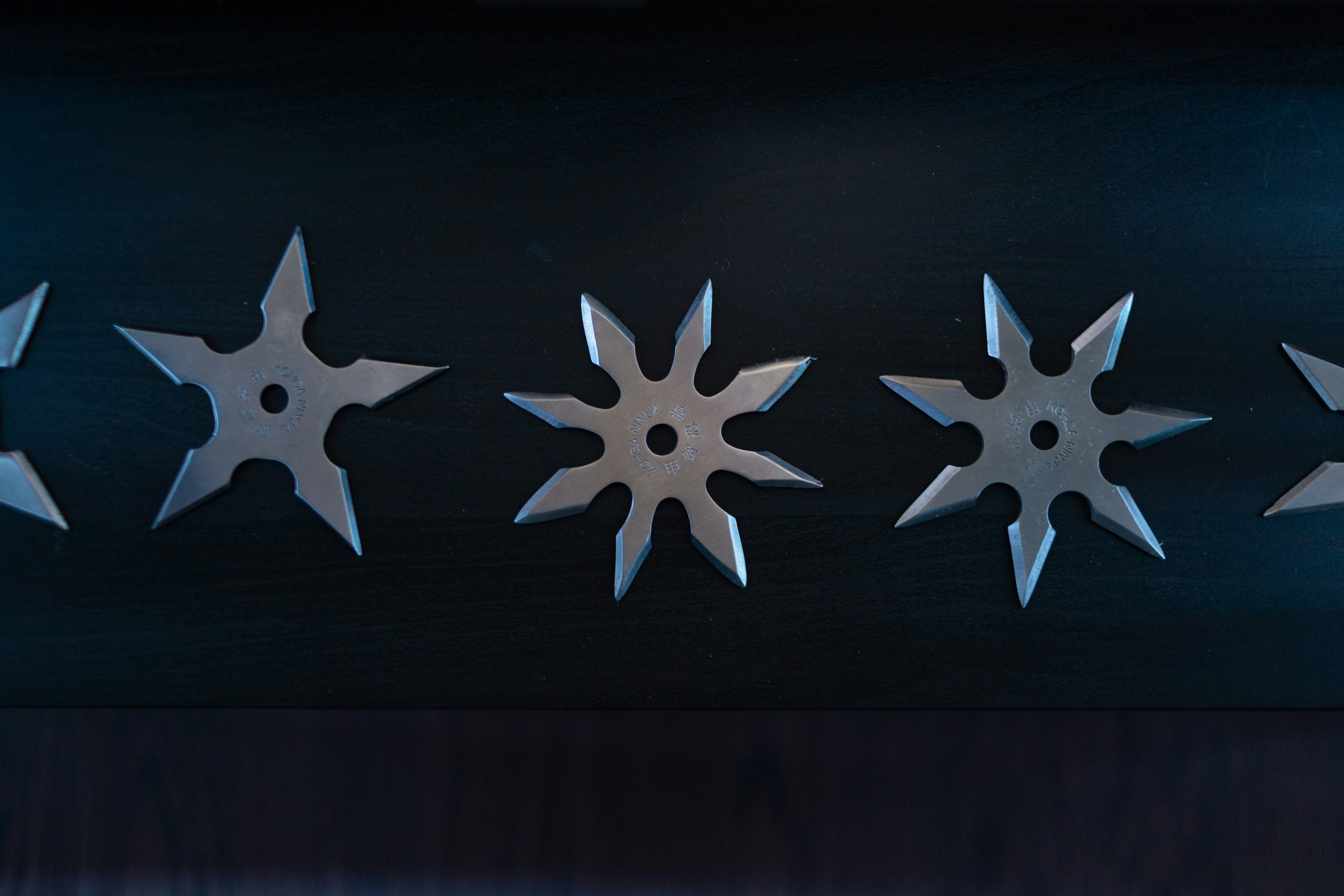 grey throwing knives on black surface