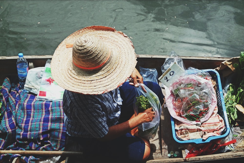 person wearing straw hat holding clear plastic pack