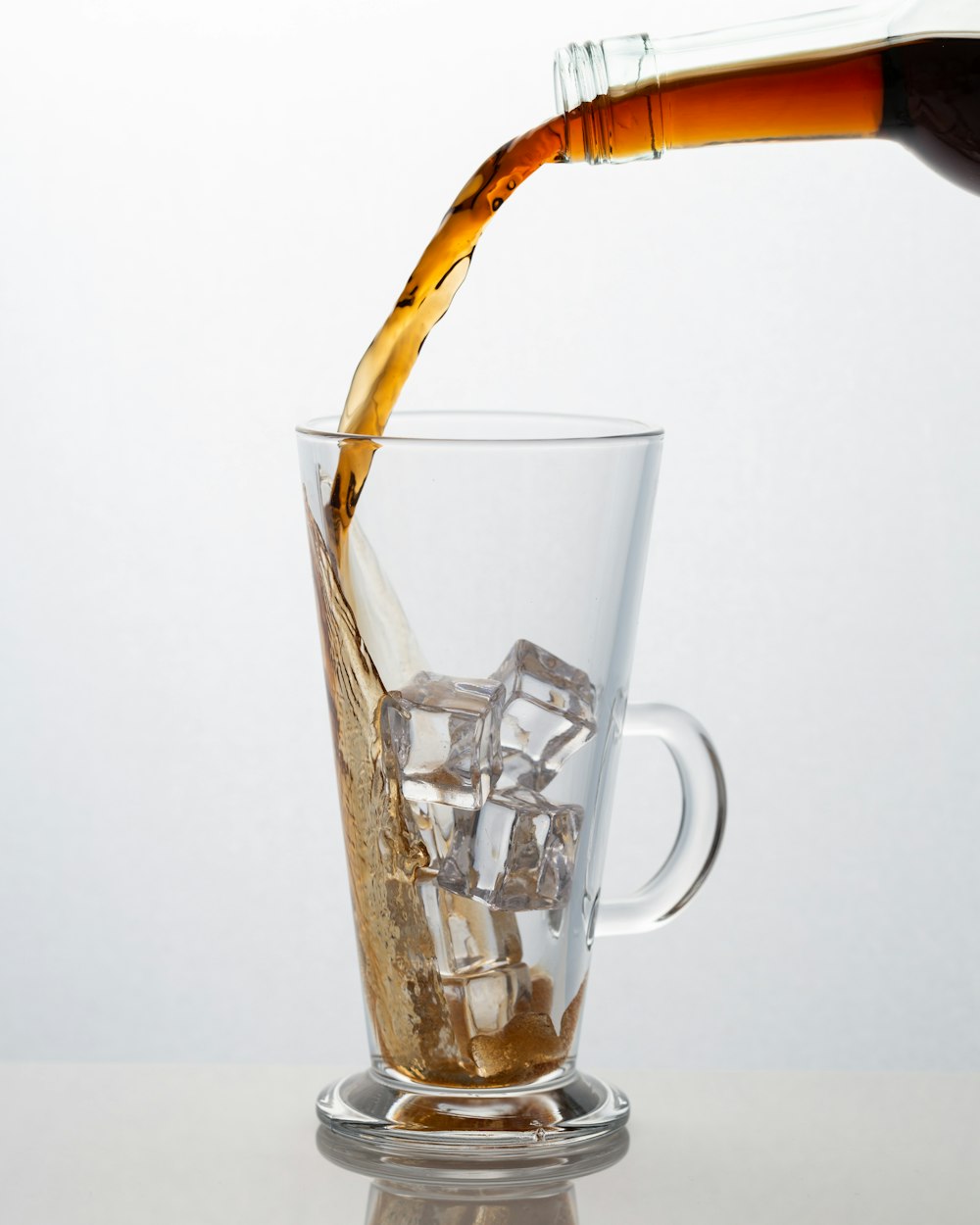 beverage pouring on clear drinking glass with ice