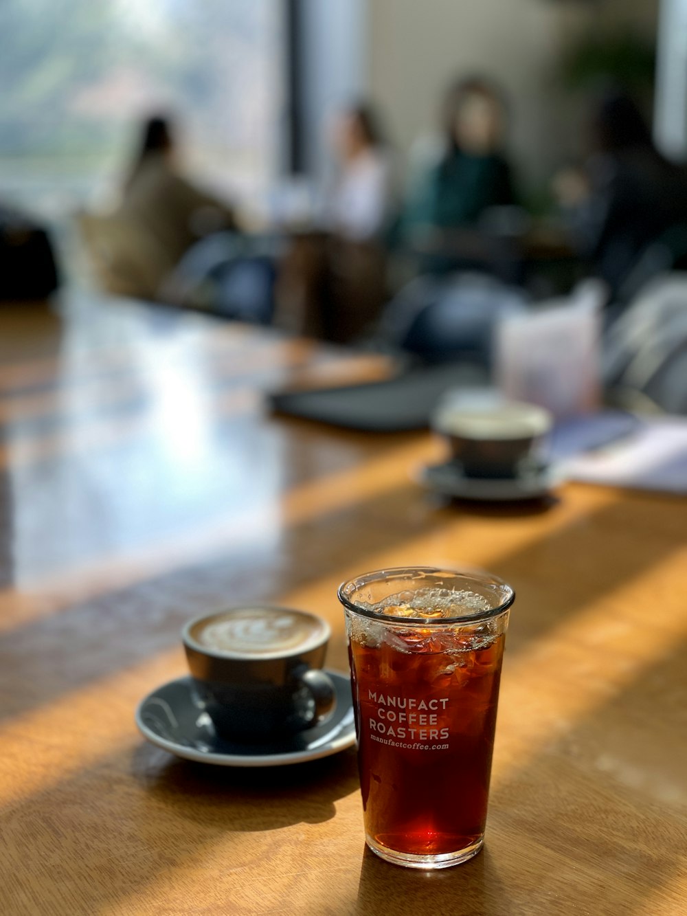 drinking glass beside teacup on brown table