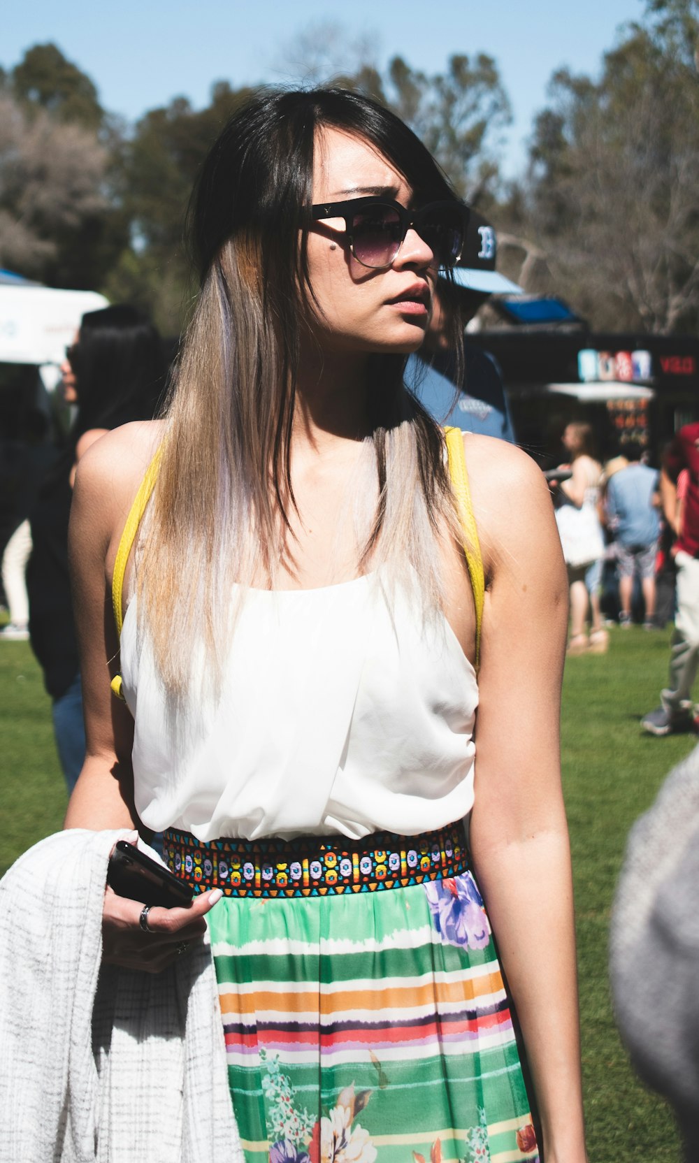 woman wearing shades, white top and colorful skirt