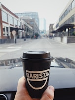 A driver enjoying a break with a coffee, parked near a scenic Portuguese street.