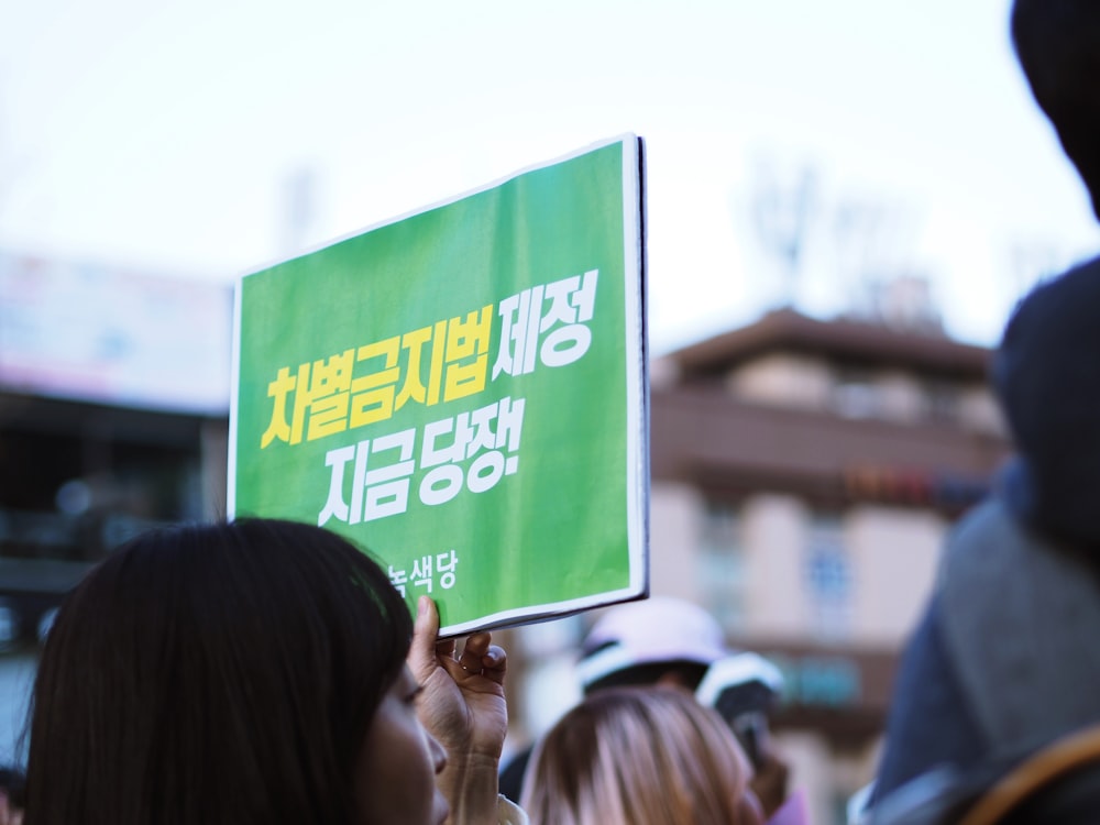 person holding up sign beside people