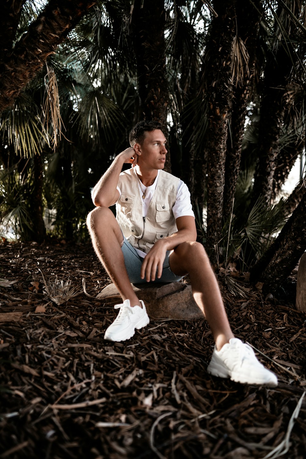 man sitting on rock beside palm trees