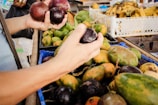 Hands selecting ripe fruits at a local market, ready for pulping.