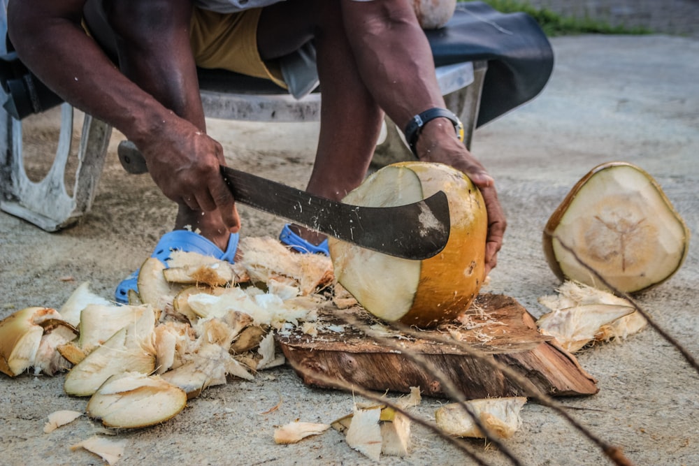 Un homme découpe une banane avec un grand couteau